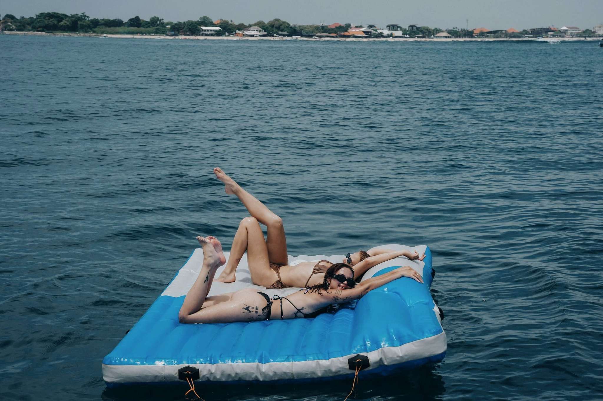 Guests on floating mat beside Freedom Yacht in crystal water