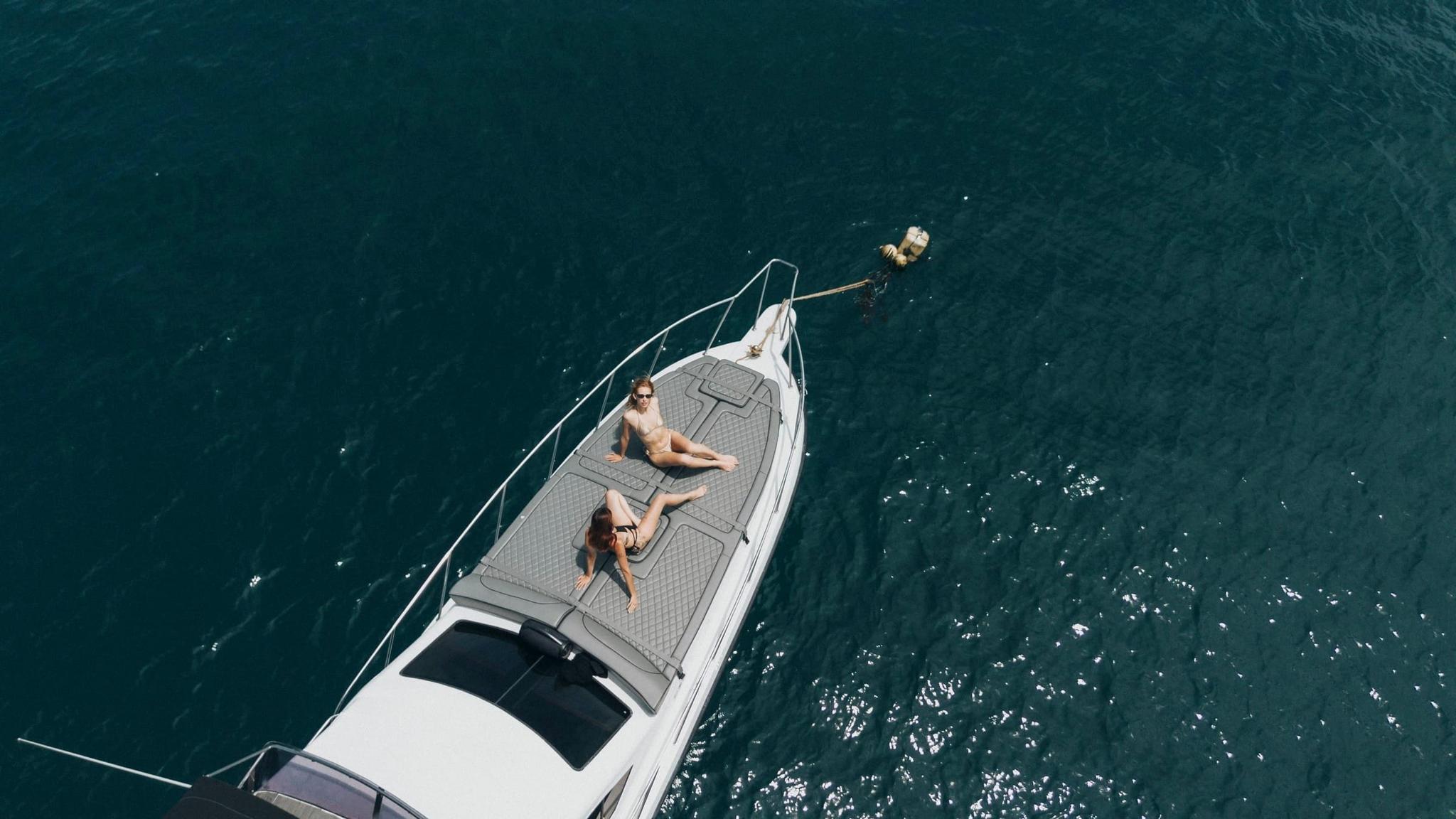 Aerial view of clear turquoise water and a yacht anchored off the Bali coast
