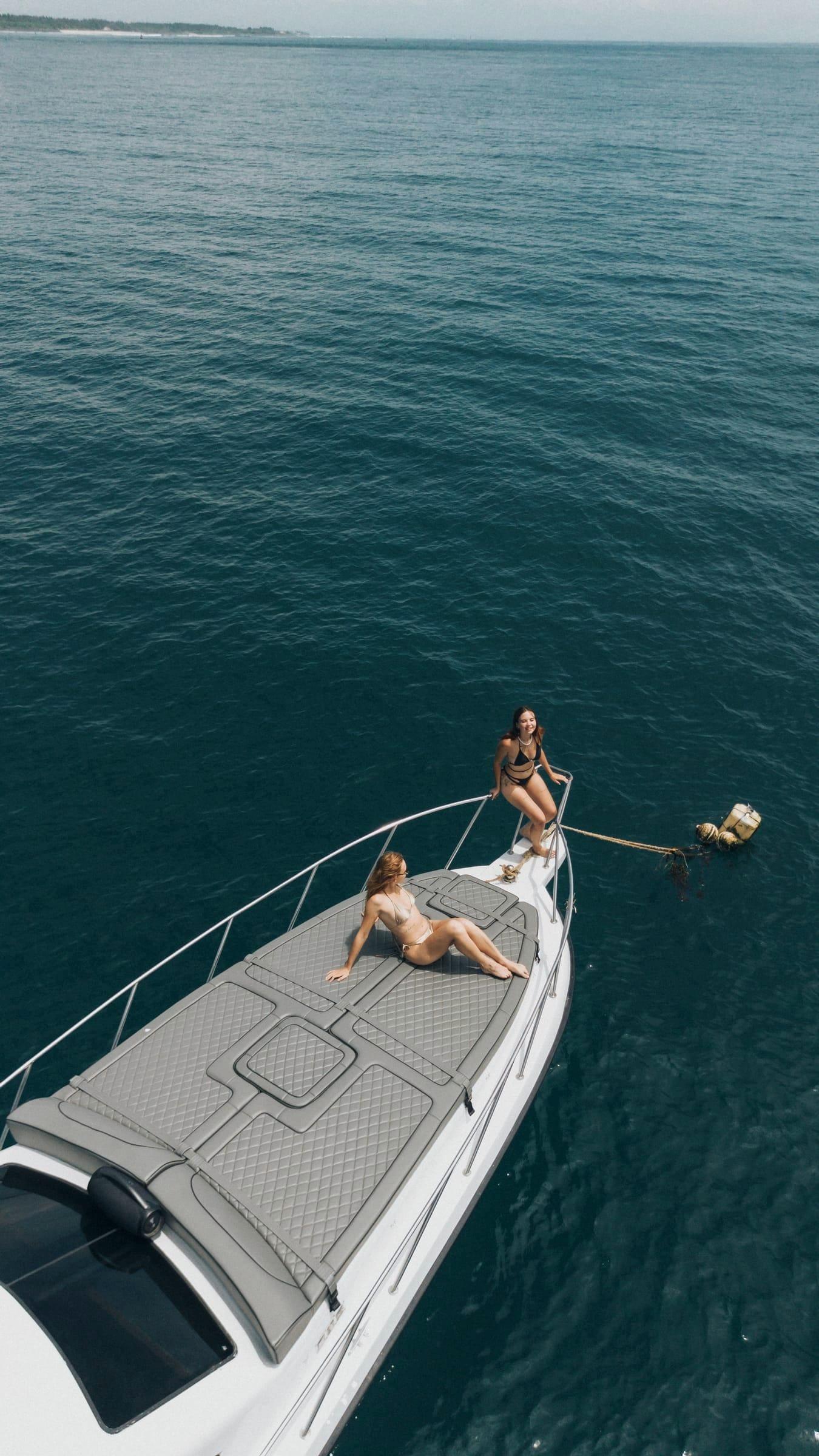 Vertical aerial view of two guests relaxing on the bow of Freedom Yacht